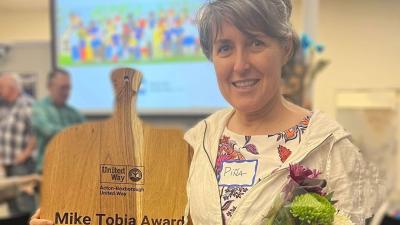 Pina Medera holding cutting board engraved with "Mike Tobia Award for Community Leadership"